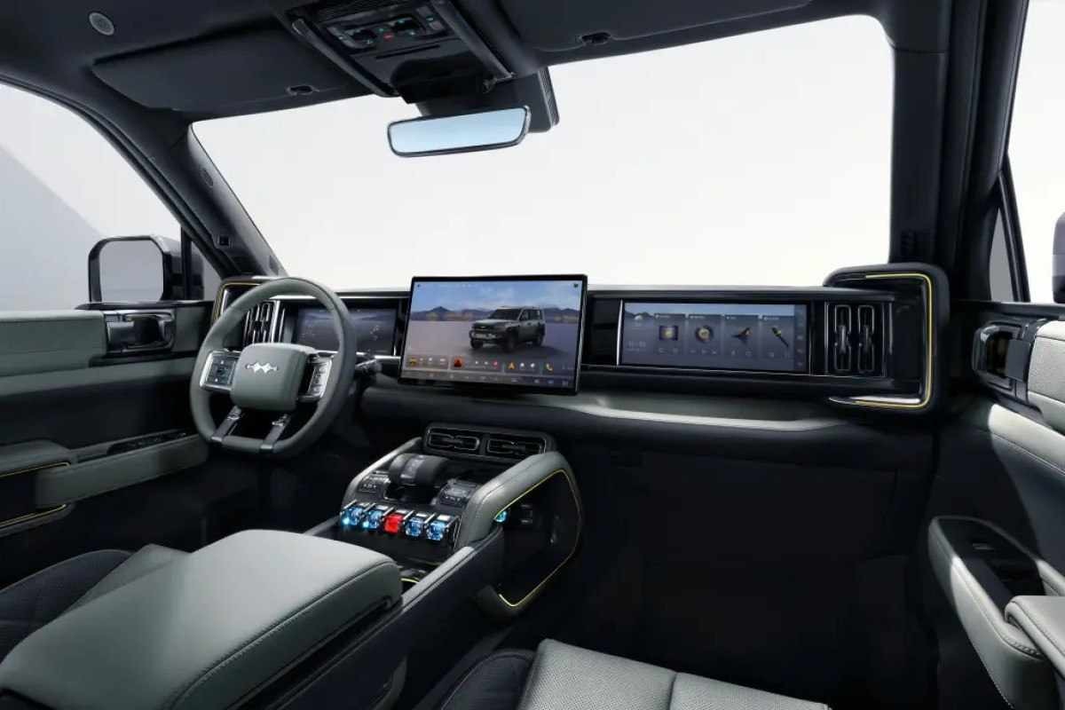 Interior do Leopard 5 com acabamento em preto e três telas no console ligadas. Um fundo branco iluminado é visto pelo para-brisas e janelas.