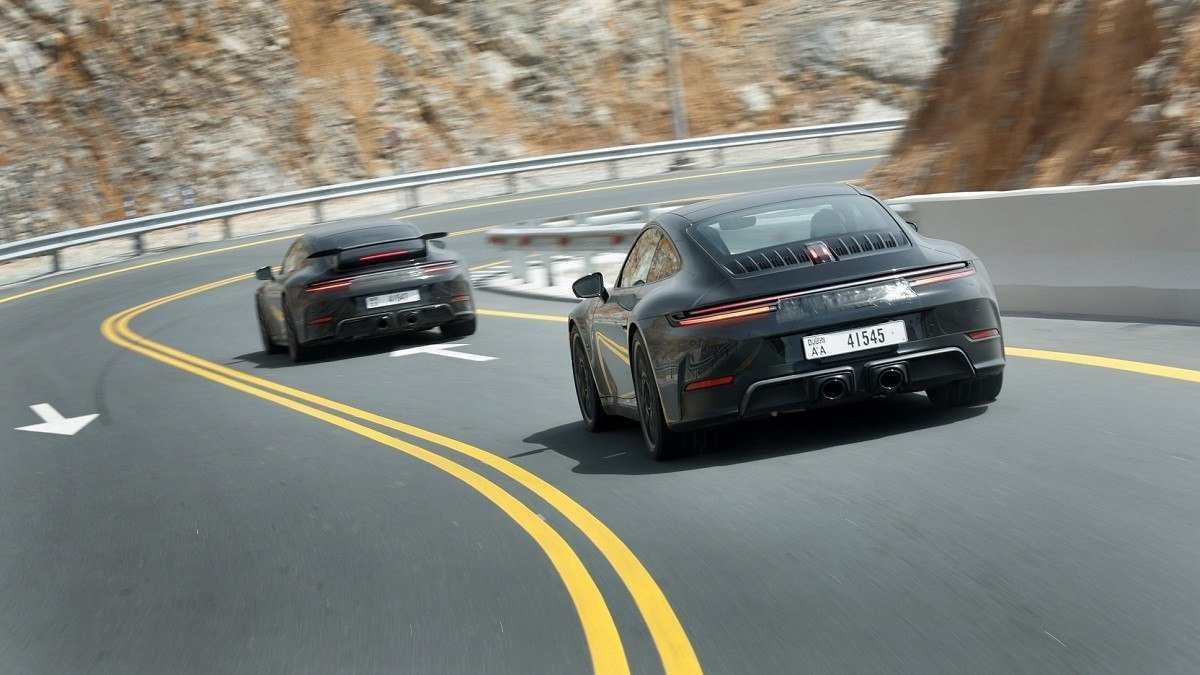 Porsche 911 híbrido preto na estrada asfaltada com montanhas nas laterais 