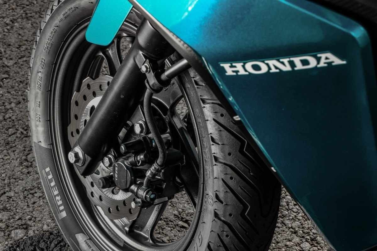 Honda Elite 125 modelo 2025 detalhe azul da roda dianteira de liga leve de 12 polegadas estática no asfalto