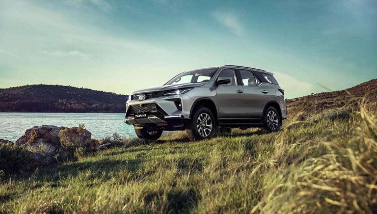 Toyota SW4 SRX Platinum cinza, de frente, estacionada sobre gramado, com lago ao fundo