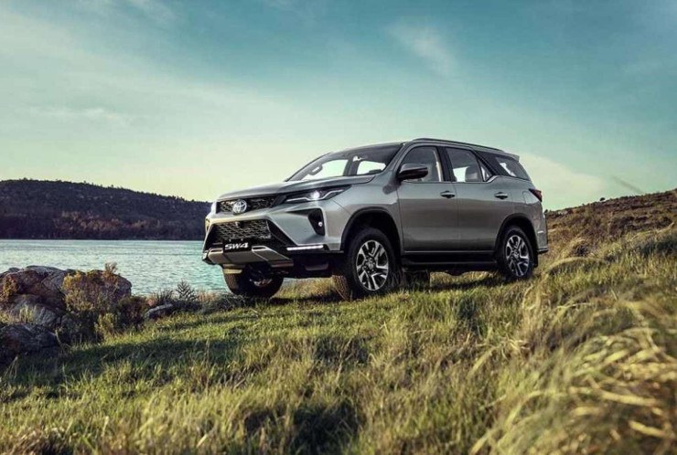 Toyota SW4 SRX Platinum cinza, de frente, estacionada sobre gramado, com lago ao fundo