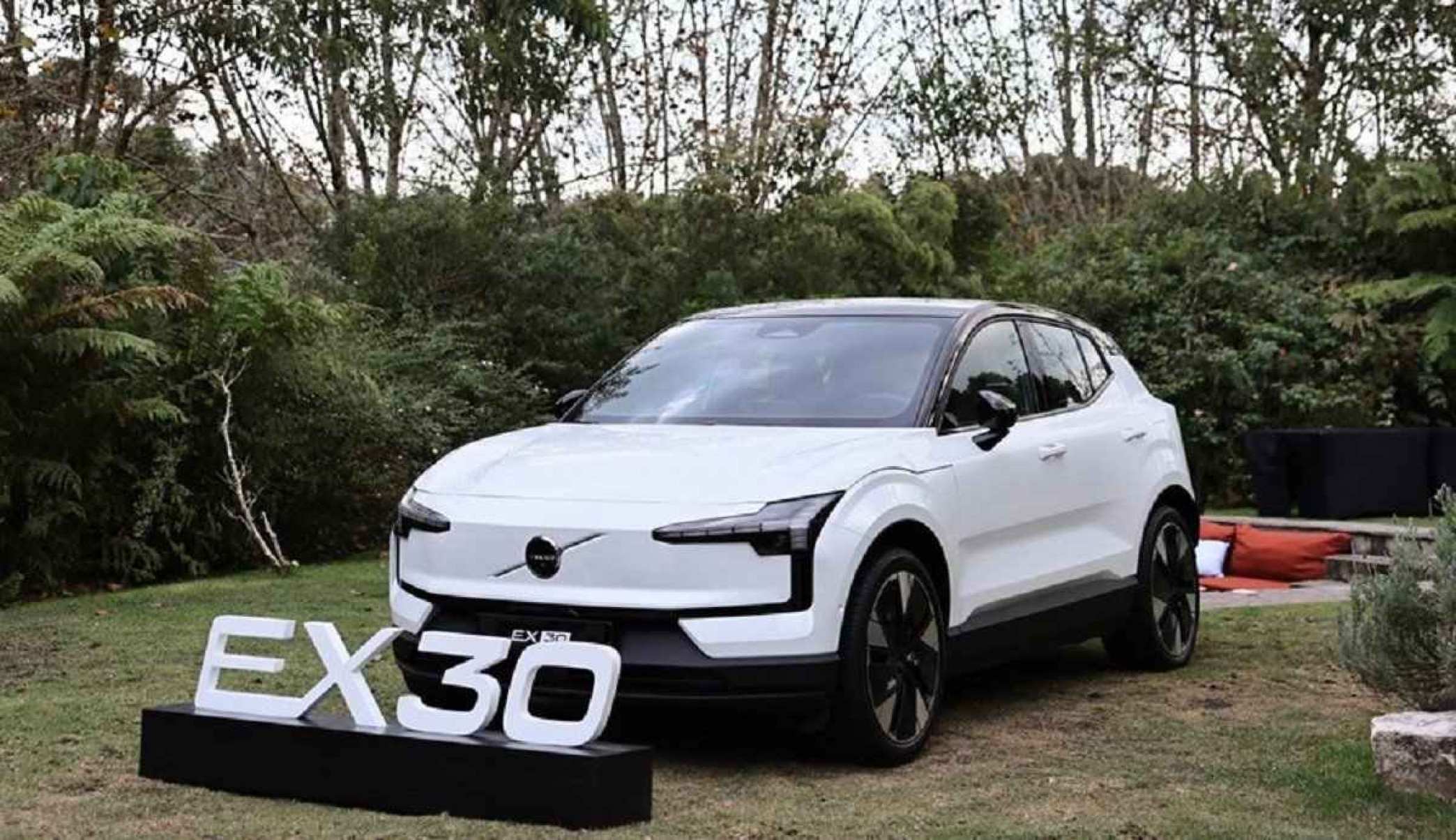 Volvo EX30 branco de frente estático em gramado com árvores ao fundo