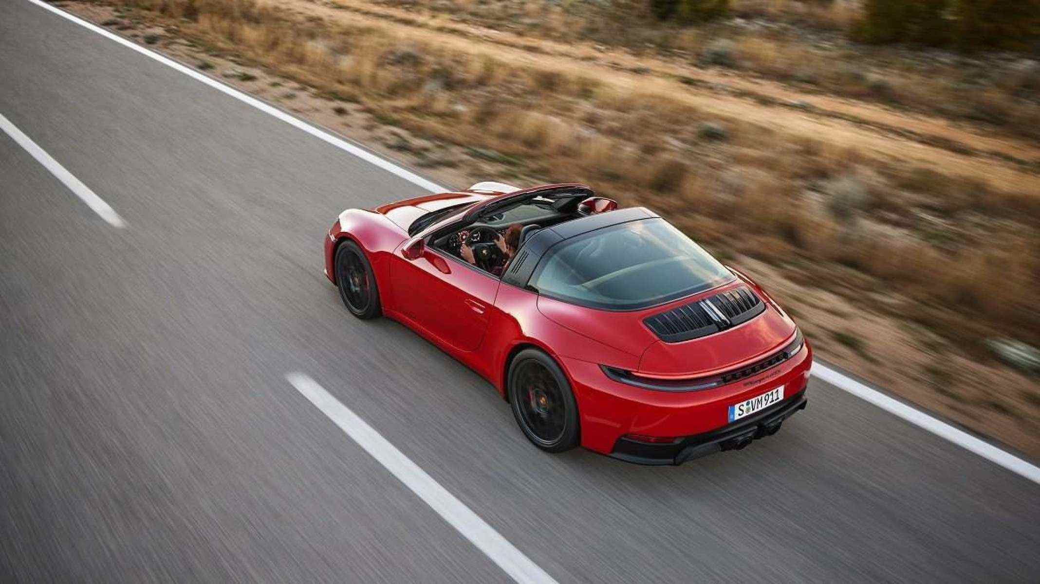 Porsche 911 Carrera GTS vermelho em movimento em estrada asfaltada com grama ao lado