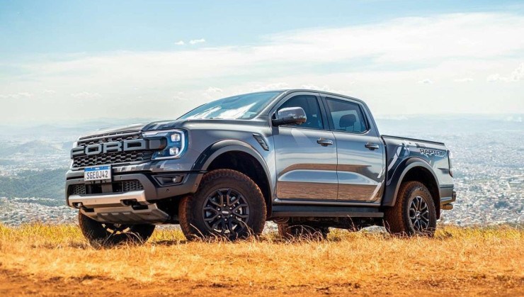 Ford Ranger Raptor 2024 cinza, de frente, estacionada em campo