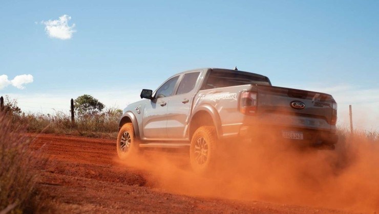 Ford Ranger Raptor 2024 cinza, de traseira, em movimento em estrada de terra