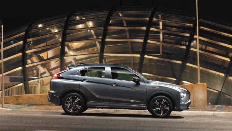Mitsubishi Eclipse Cross HPE S modelo 2023 cinza de lateral estático no asfalto com imóvel envidraçado ao fundo em São Paulo
