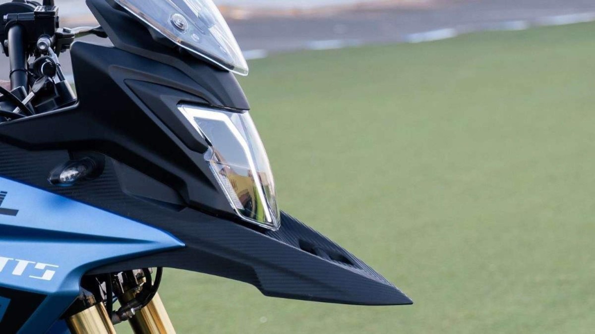 Motocicleta elétrica Watts W-Trail azul e preta modelo 2024 detalhe do para-lama, farol e pára-brisa estático no gramado