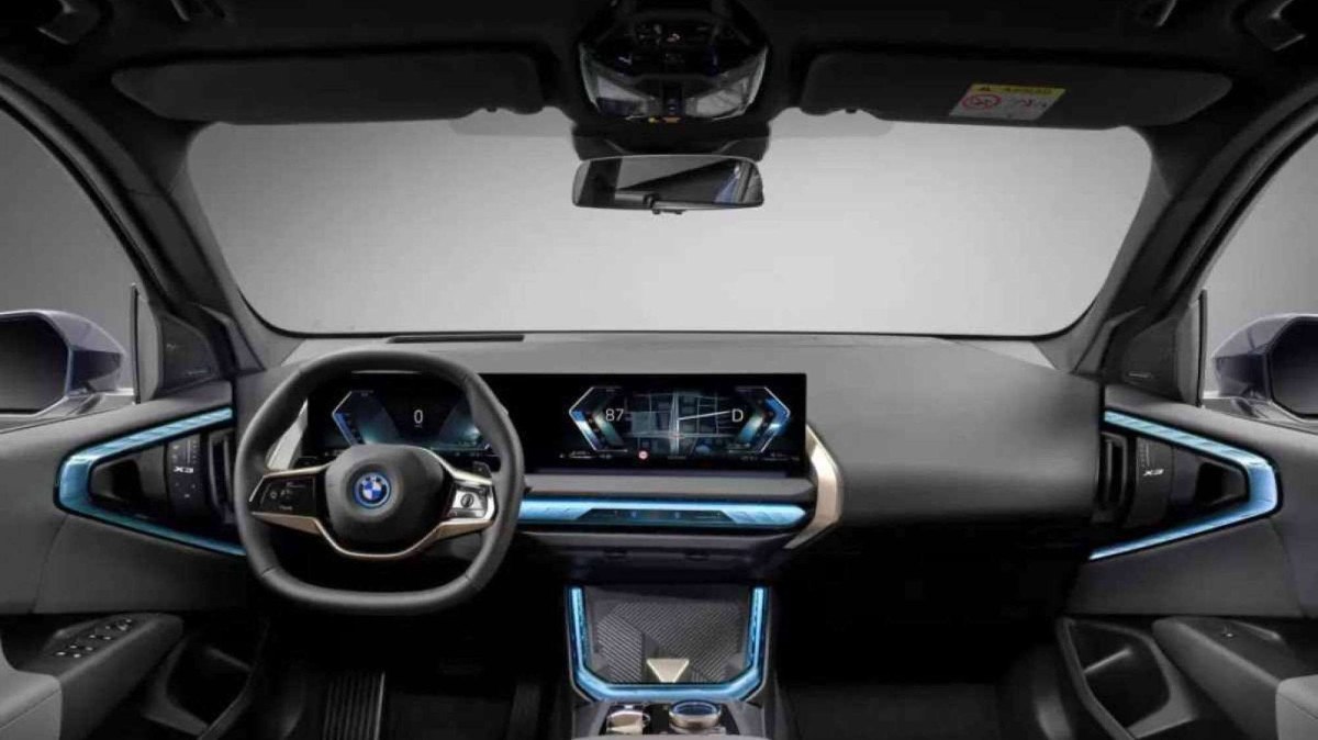 O interior premium do carro apresenta tela curva com volante giratório central, sistema de navegação BMW Maps e iluminação ambiente multicolorida
