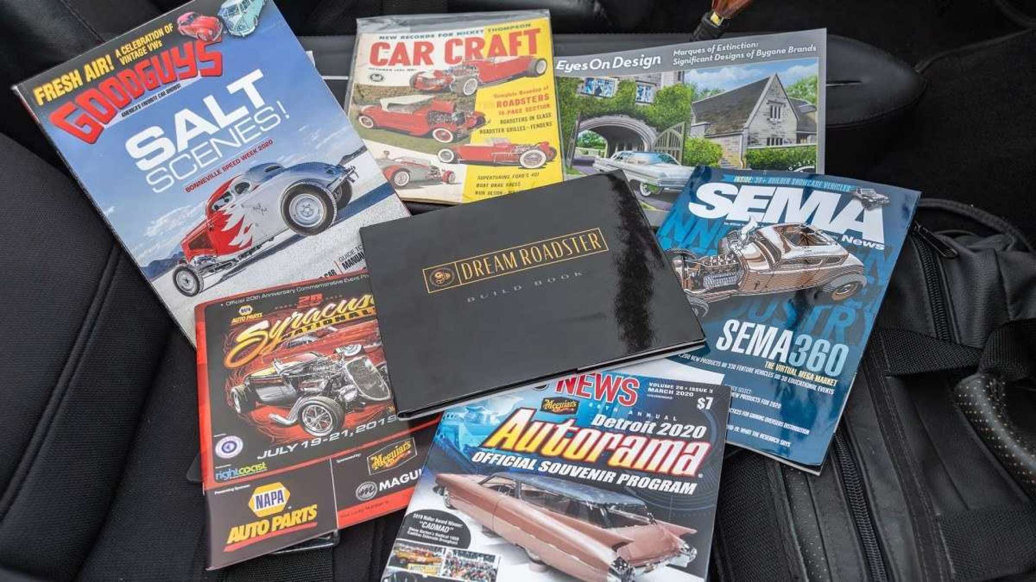 Diversas revistas e cadernos de fotos em cima de banco de couro do Hot Wheels Golden Hawk Dream Roadster