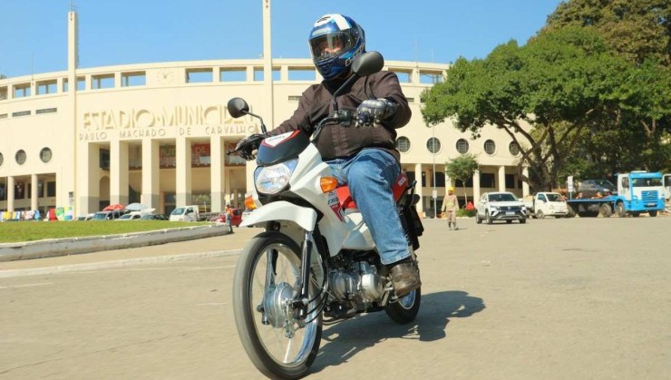 Honda Pop 110i 2025 branca com detalhes em vermelho e preto de frente em movimento no asfalto
