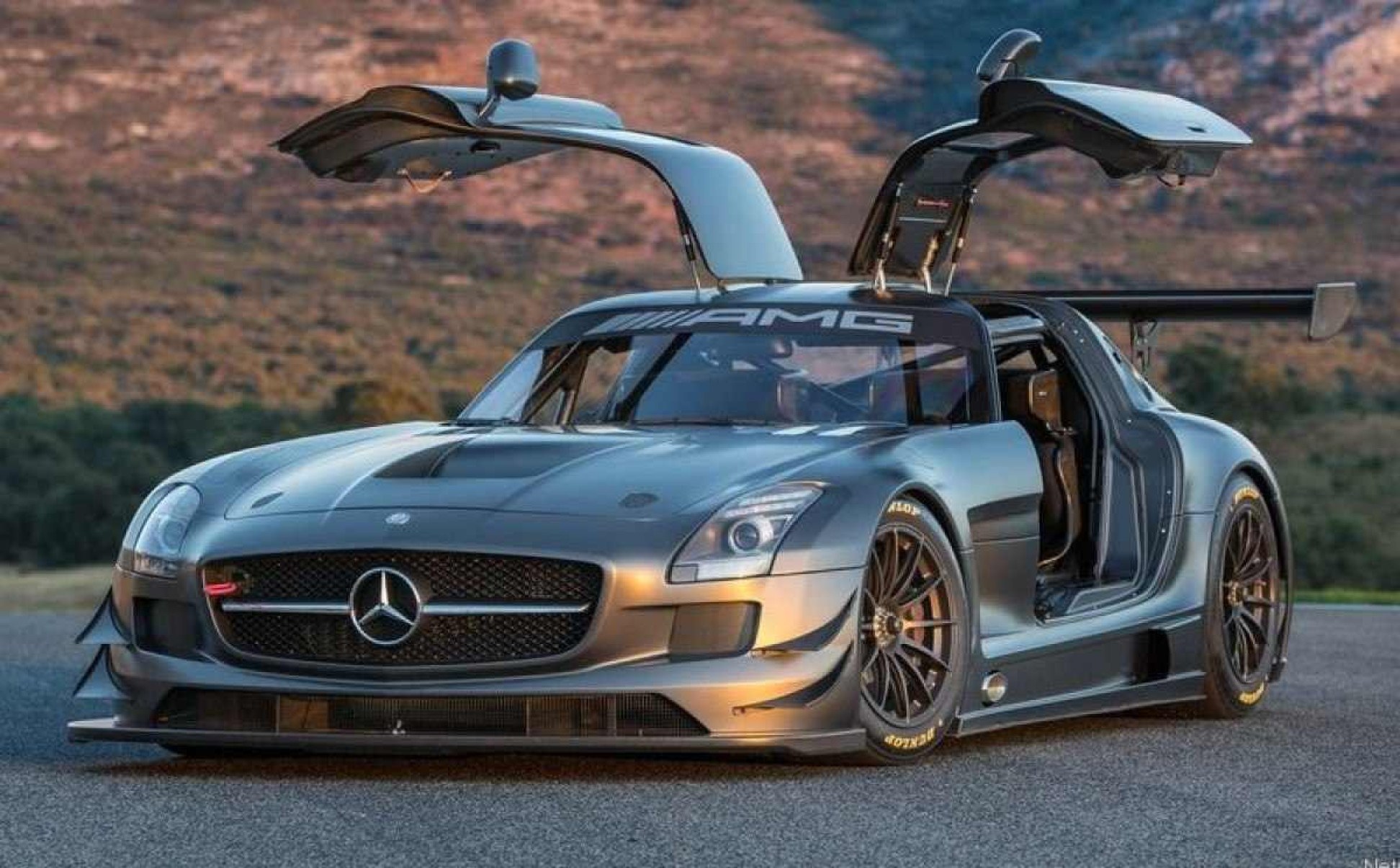Mercedes-AMG SLS prateado com frente estática e portas asa de gaivota abertas no asfalto