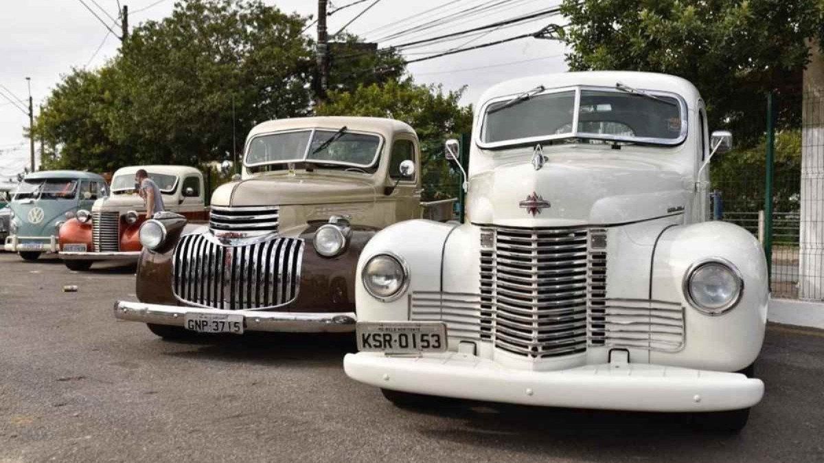 Encontro de Carros Antigos em Betim com caminhões Chevrolet e uma Kombi posicionada no estacionamento