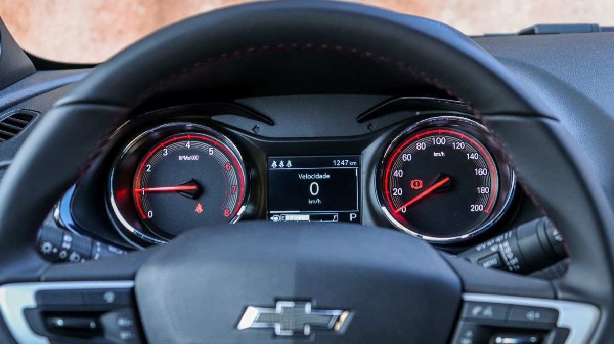 Chevrolet Onix RS modelo 2022 vermelho interior painel de instrumentos com detalhes vermelho e volante estático no asfalto