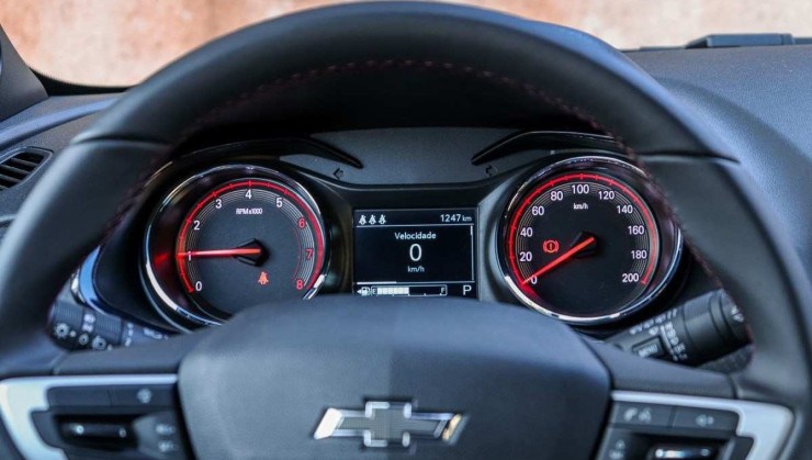 Chevrolet Onix RS modelo 2022 vermelho interior painel de instrumentos com detalhes vermelho e volante estático no asfalto