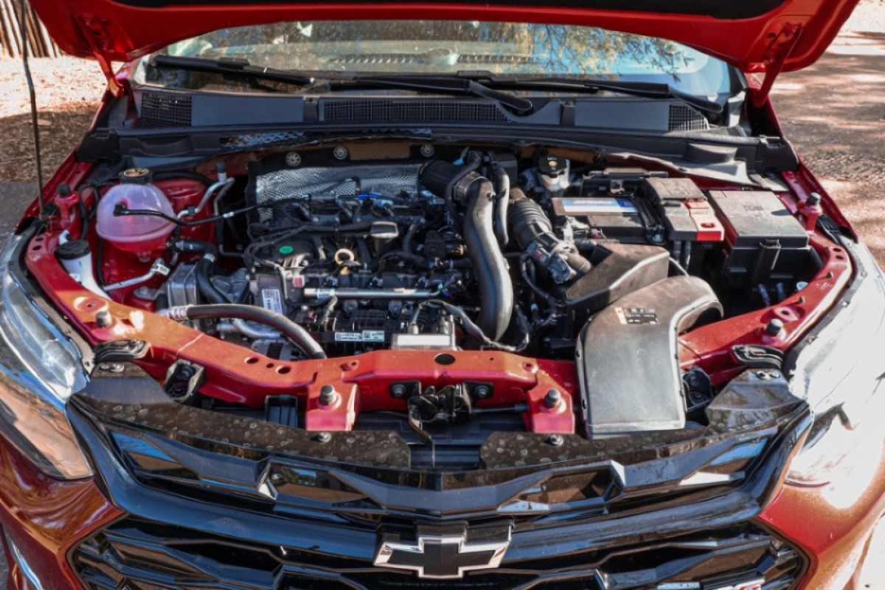 Chevrolet Onix RS modelo 2022 vermelho de frente cofre do motor turbo estático no asfalto