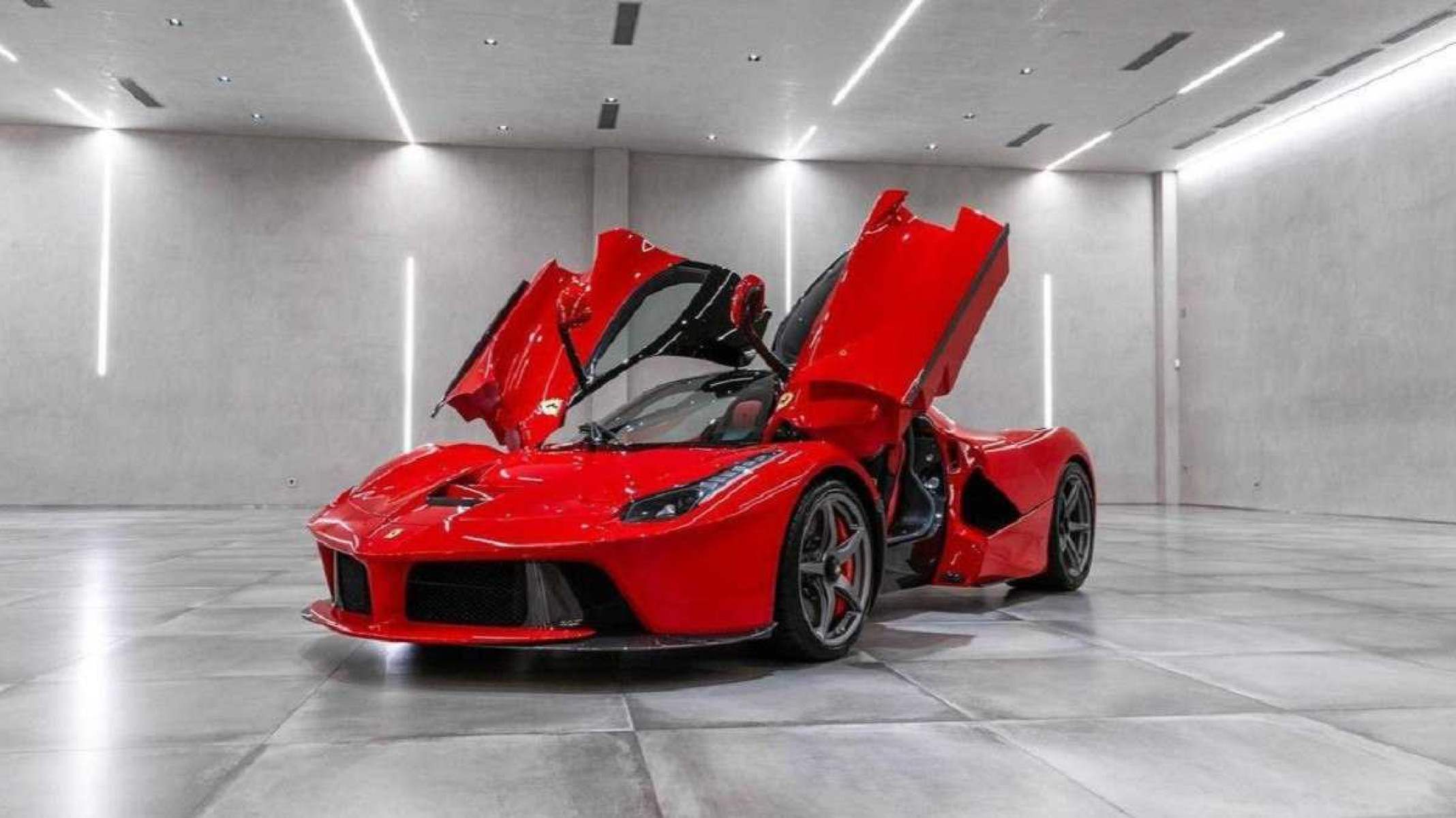 Ferrari LaFerrari vermelha de frente estática em sala cinza iluminada