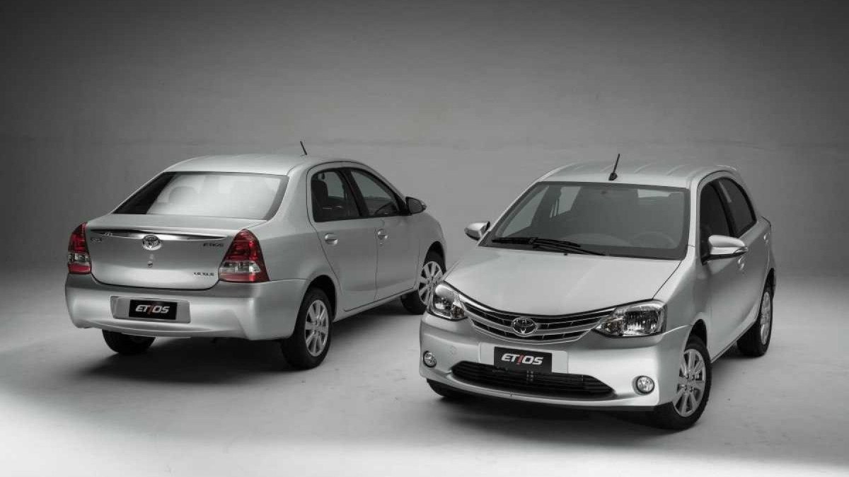 Toyota Etios Sedan prata de traseira e hatch prata de frente estáticos no estúdio