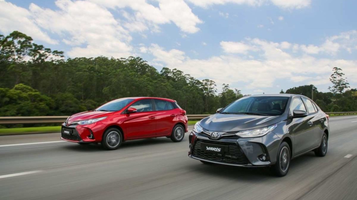 Toyota Yaris hatch, vermelho, e sedan, cinza: os dois veículos estão de frente e transitam lado a lado por rodovia asfaltada 