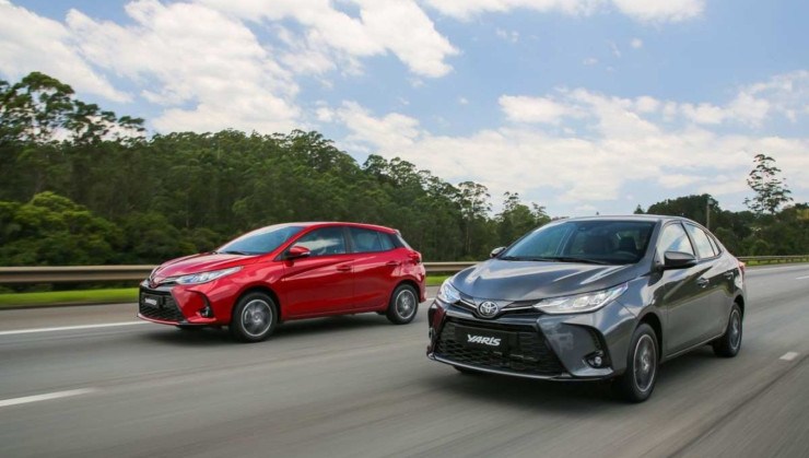 Toyota Yaris hatch, vermelho, e sedan, cinza: os dois veículos estão de frente e transitam lado a lado por rodovia asfaltada 