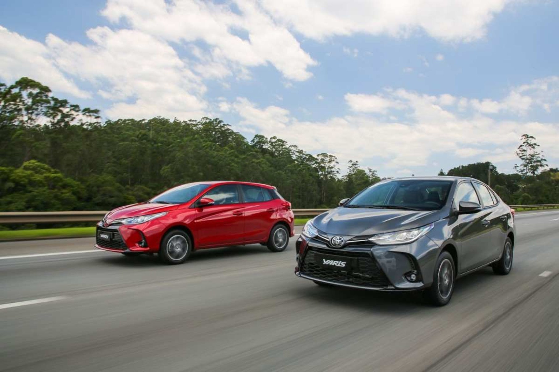 Toyota Yaris hatch, vermelho, e sedan, cinza: os dois veículos estão de frente e transitam lado a lado por rodovia asfaltada 