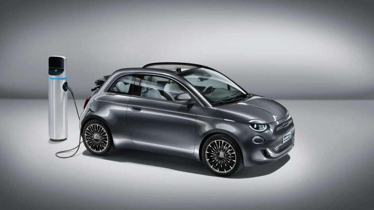 Fiat 500 Electric Cabriolet modelo 2020 prata com capota aberta conectada ao carregador em fundo cinza em estúdio