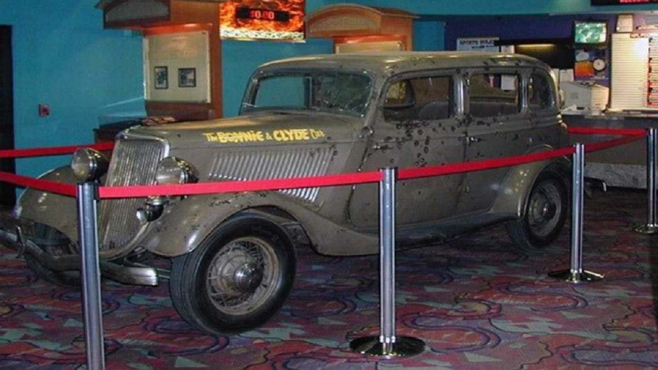 Ford V8 estacionado em museu lateralmente dentro de uma fita vermelha em museu