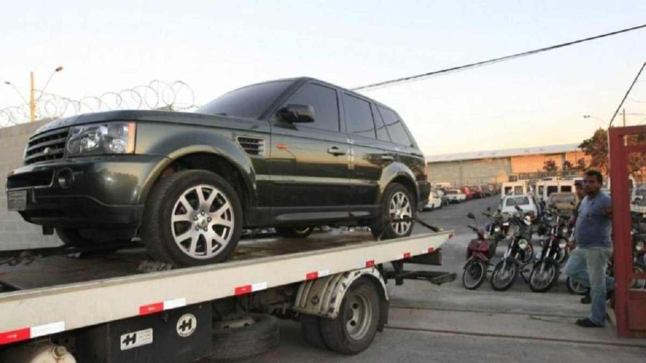 Land Rover Sport 3.0 SE, ano 2011, na cor verde saindo de uma garagem em cima de um caminhão 