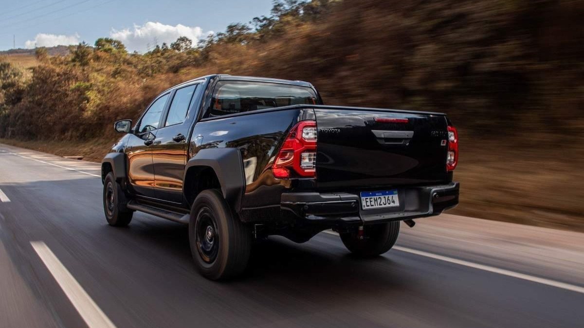 Toyota Hilux GR-Sport preta, de traseira, em movimento em rodovia asfaltada