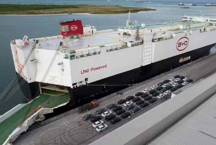 Navio branco parado em porto com carros ao lado 