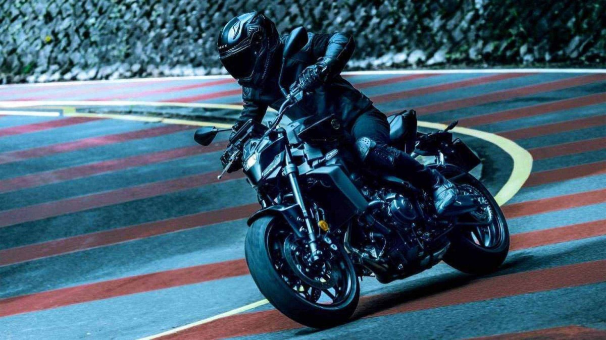 Yamaha MT-09 Y-AMT modelo 2024 frente preta movendo-se no asfalto em curva com listras vermelhas no chão