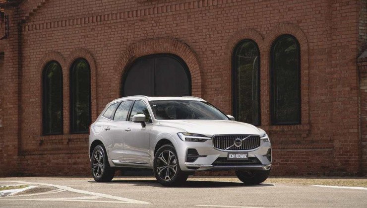 Volvo XC60 cinza, de frente, estacionado, com construção de tijolinhos ao fundo