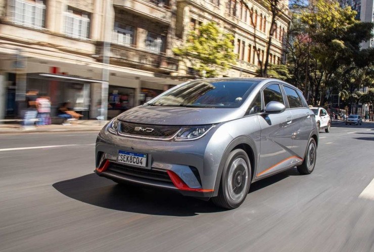 BYD Dolphin EV cinza, de frente, em movimento em via urbana