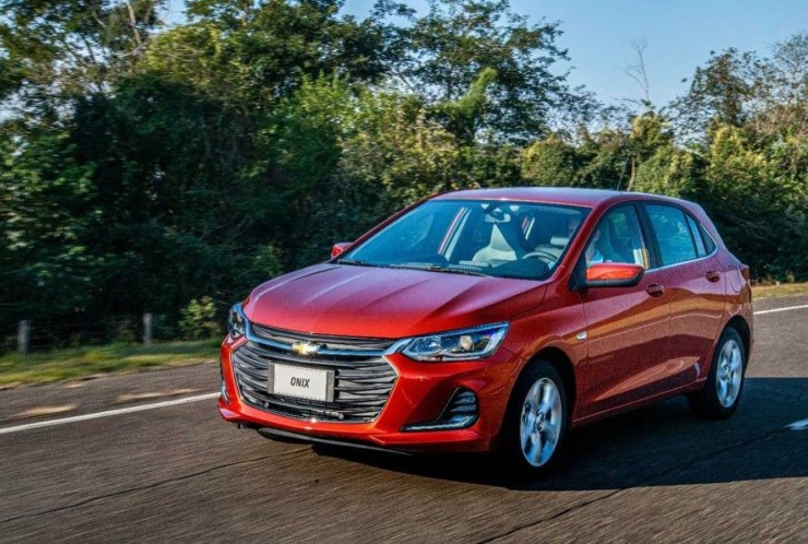 Chevrolet Onix 2020 Hatch vermelho, de frente, em movimento em via asfaltada; Chevrolet Onix é um dos hatches compactos mais vendidos do Brasil