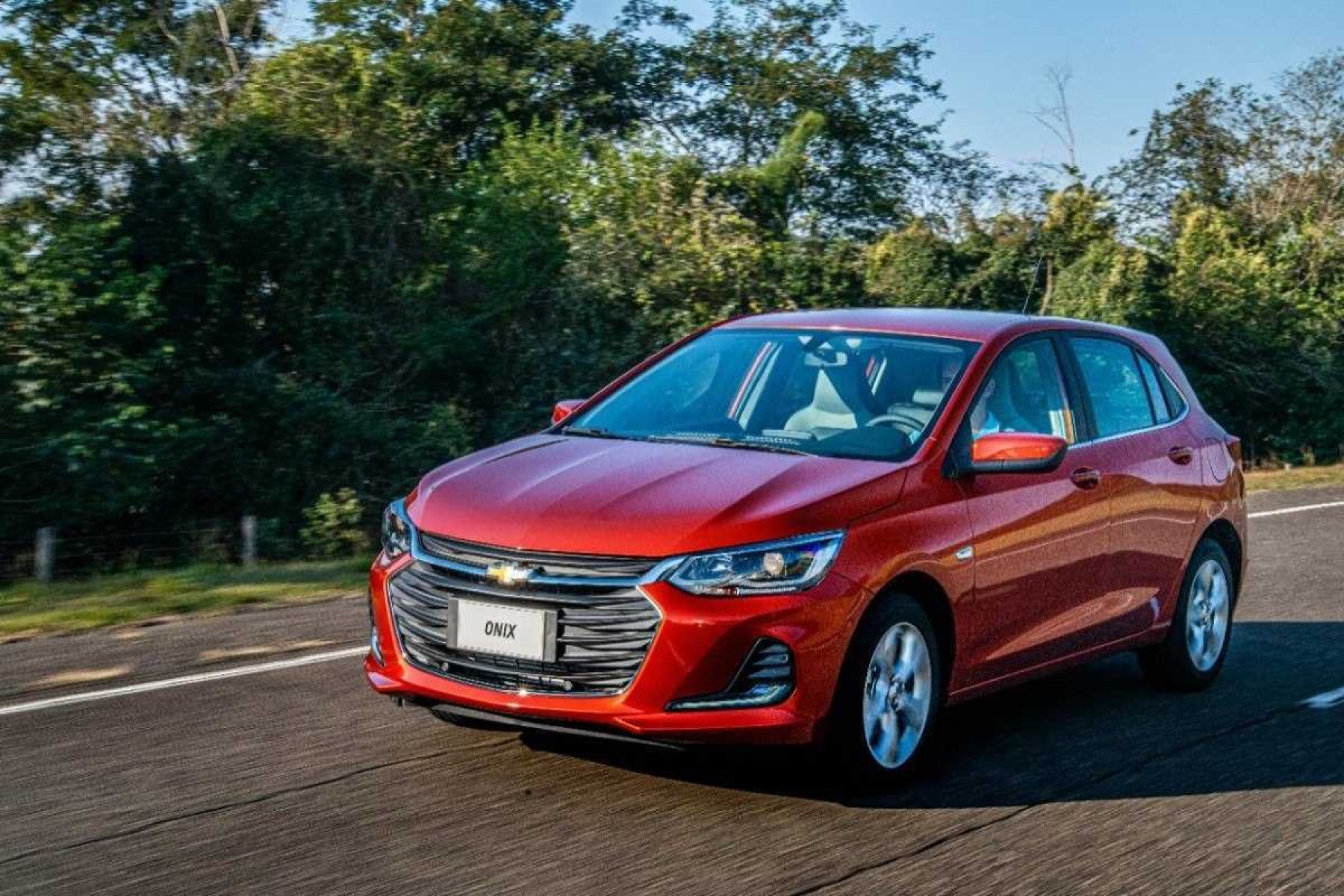 Chevrolet Onix 2020 Hatch vermelho, de frente, em movimento em via asfaltada