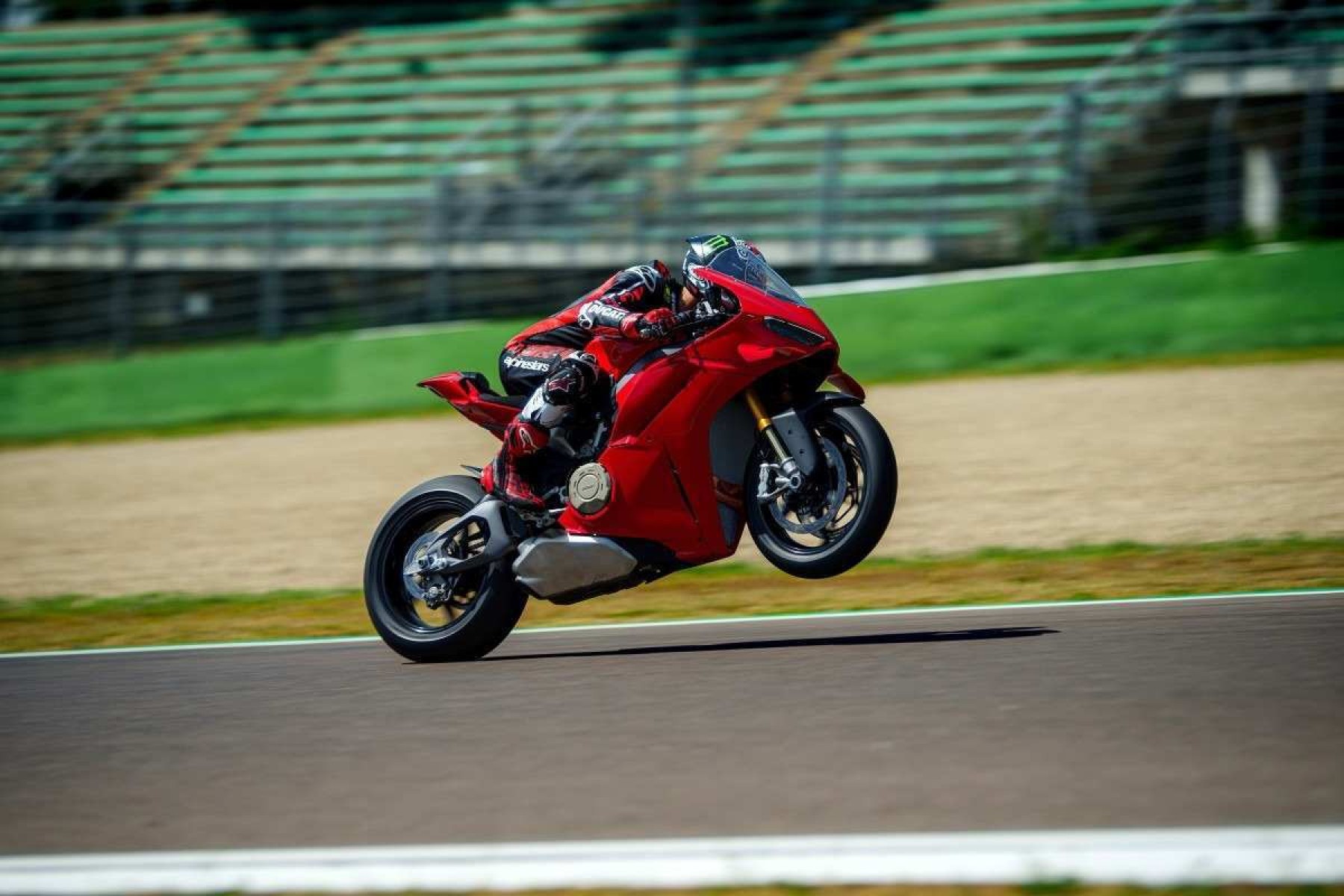 Ducati Panigale V4 S 2025 vermelha de lateral em movimento empinando a frente com roda dianteira no ar no autódromo
