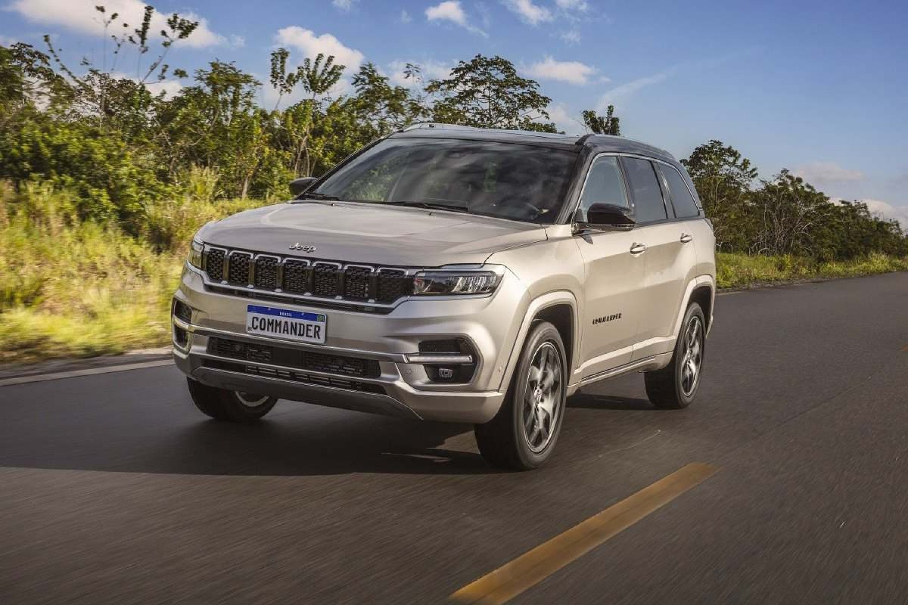 Comandante do Jeep Branco, de frente, movendo-se em uma estrada pavimentada