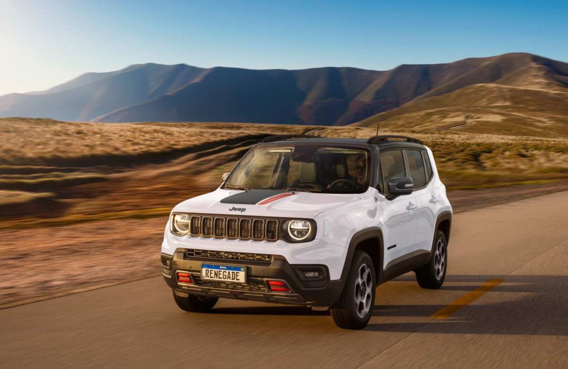 Jeep Renegade Trailhawk modelo 2025 branco com teto preto de frente em movimento na terra