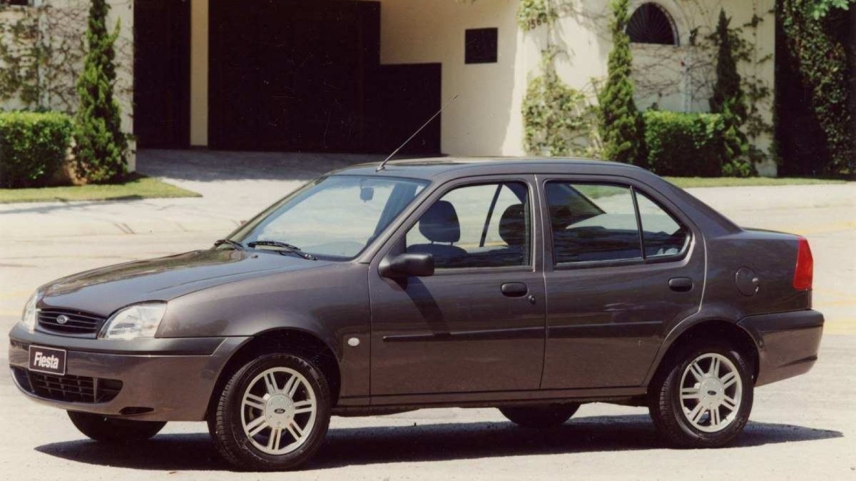 Ford Fiesta Steet Sedan 2002 cinza, de lado, estacionado em frente a residência de alto padrão