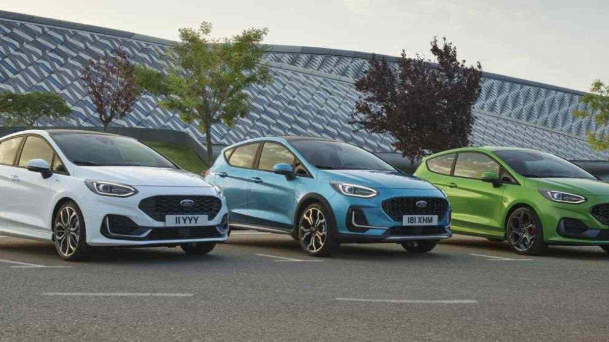 Três Ford Fiesta branco azul e verde, todos de frente, estáticos no asfalto