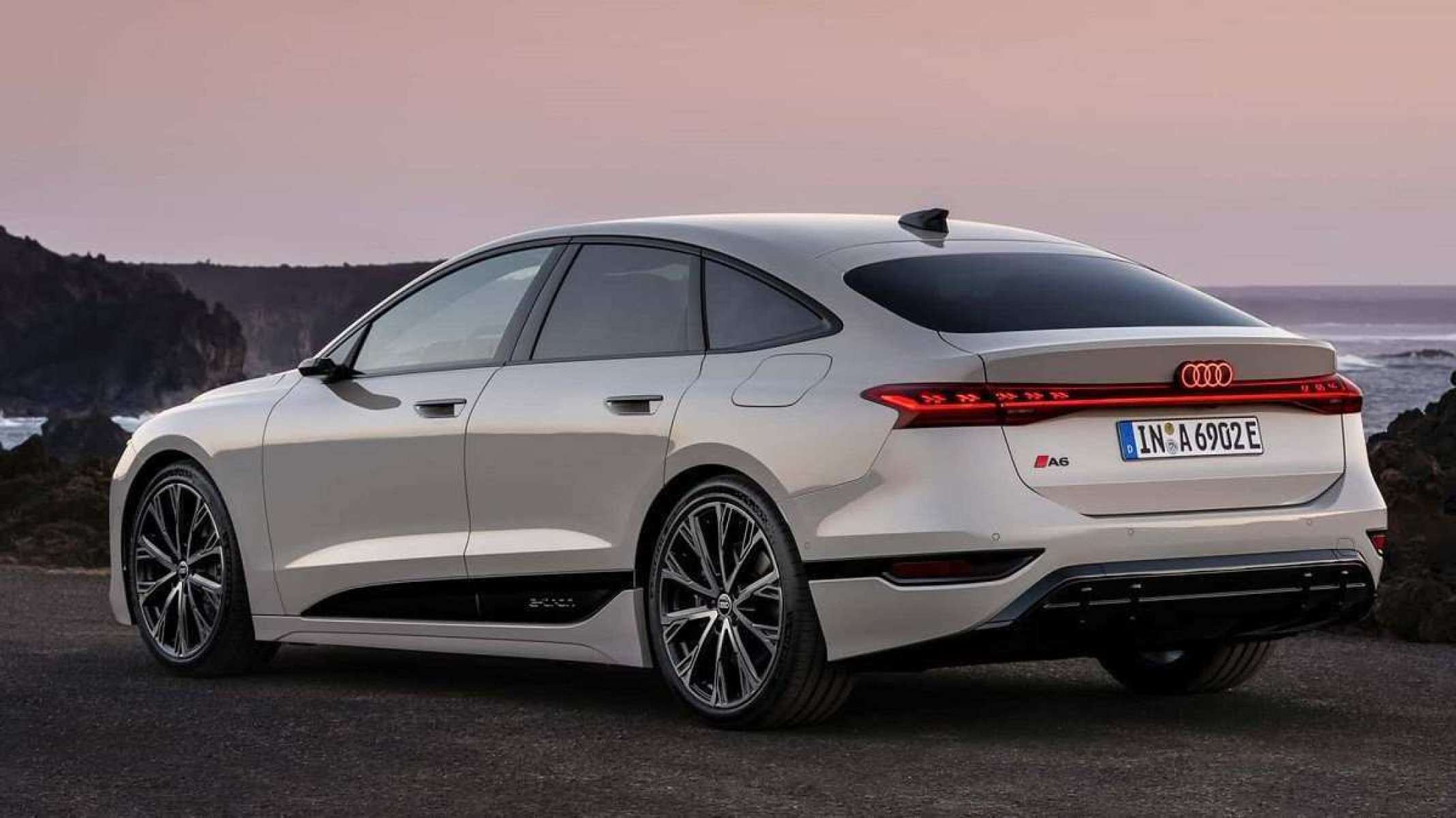 Vista traseira de um Audi A6 e-tron Sportback branco parado com uma paisagem de montanhas e céu rosa ao fundo