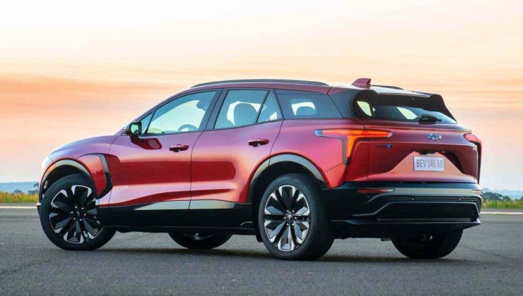 Chevrolet Blazer EV vermelho parado em rua asfaltada com céu alaranjado ao fundo.
