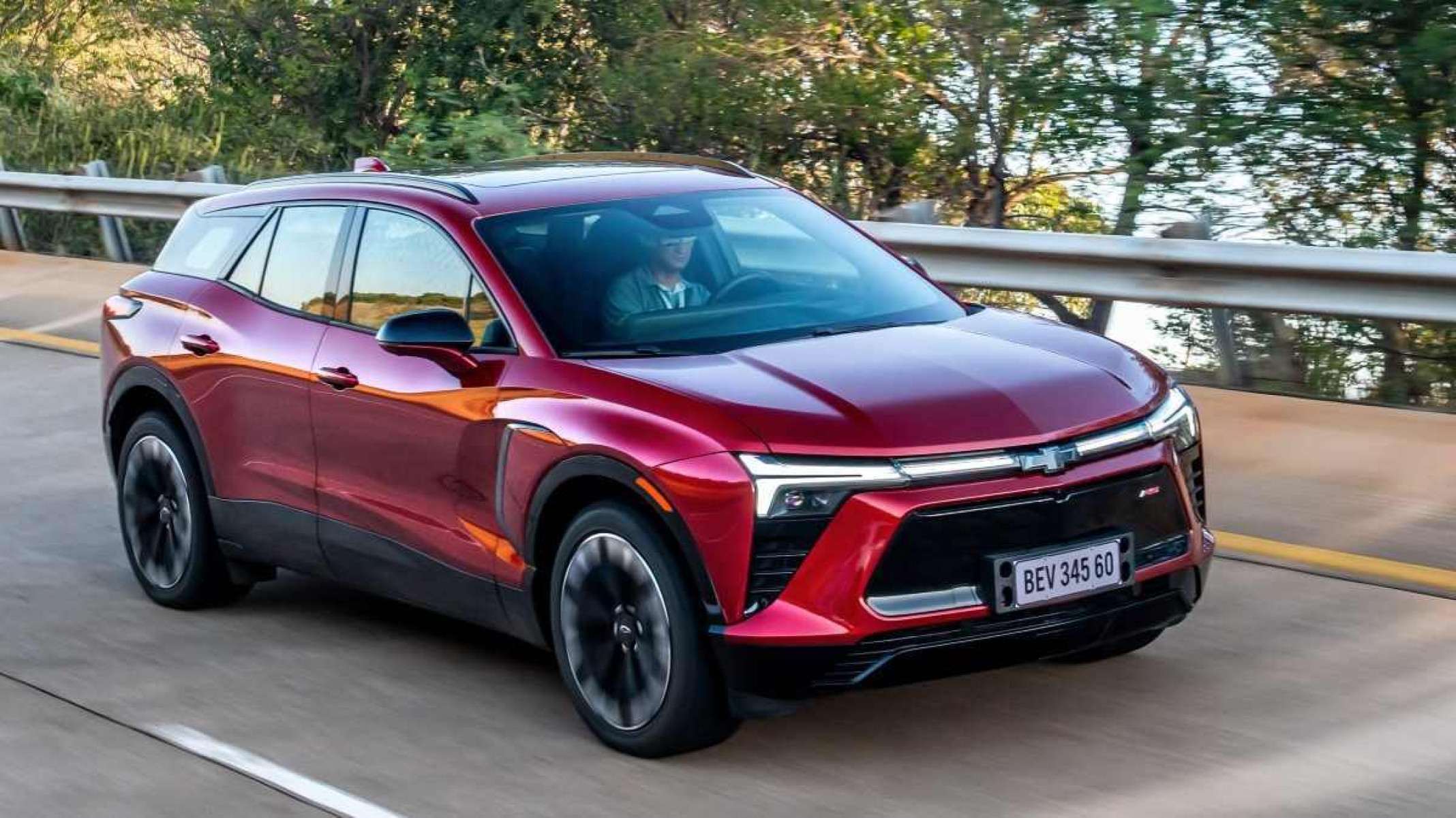 Red Chevrolety Blazer EV de frente movendo-se em uma rodovia pavimentada com árvores ao fundo