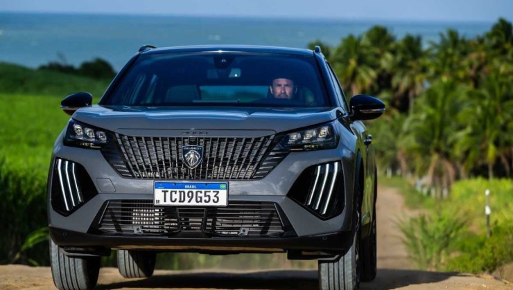 Peugeot 2008 modelo 2025 cinza de frente chapada em movimento na terra