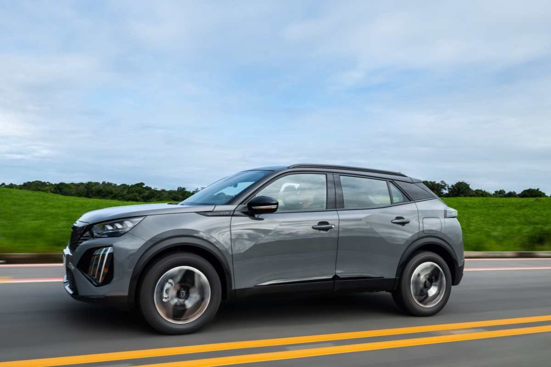 Peugeot 2008 modelo 2025 cinza de lateral em movimento no asfalto