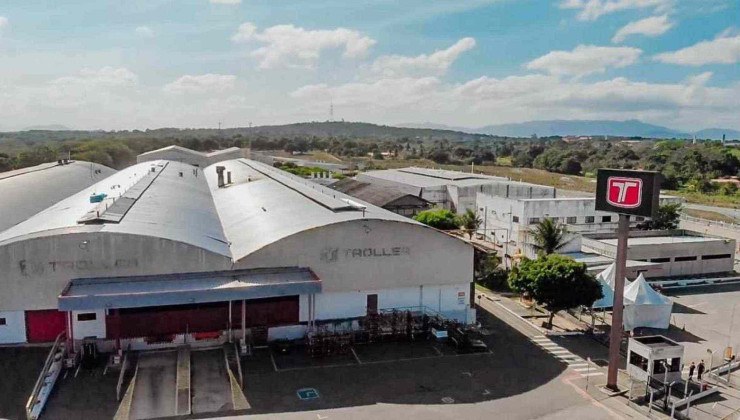 Fábrica da Troller no Ceará galpão pintado de branco cercado por grades e placa com a marca Troller