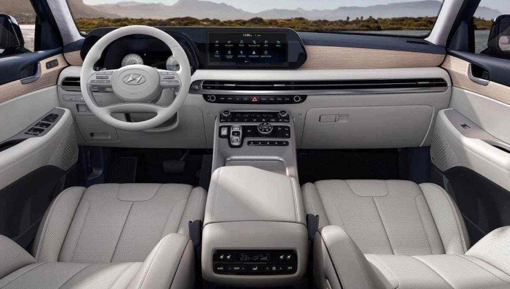 Interior de Hyundai Palisade com couro em branco e detalhes em preto. Pelo para-brisas é possível ver lago com montanha coberta por árvores ao fundo