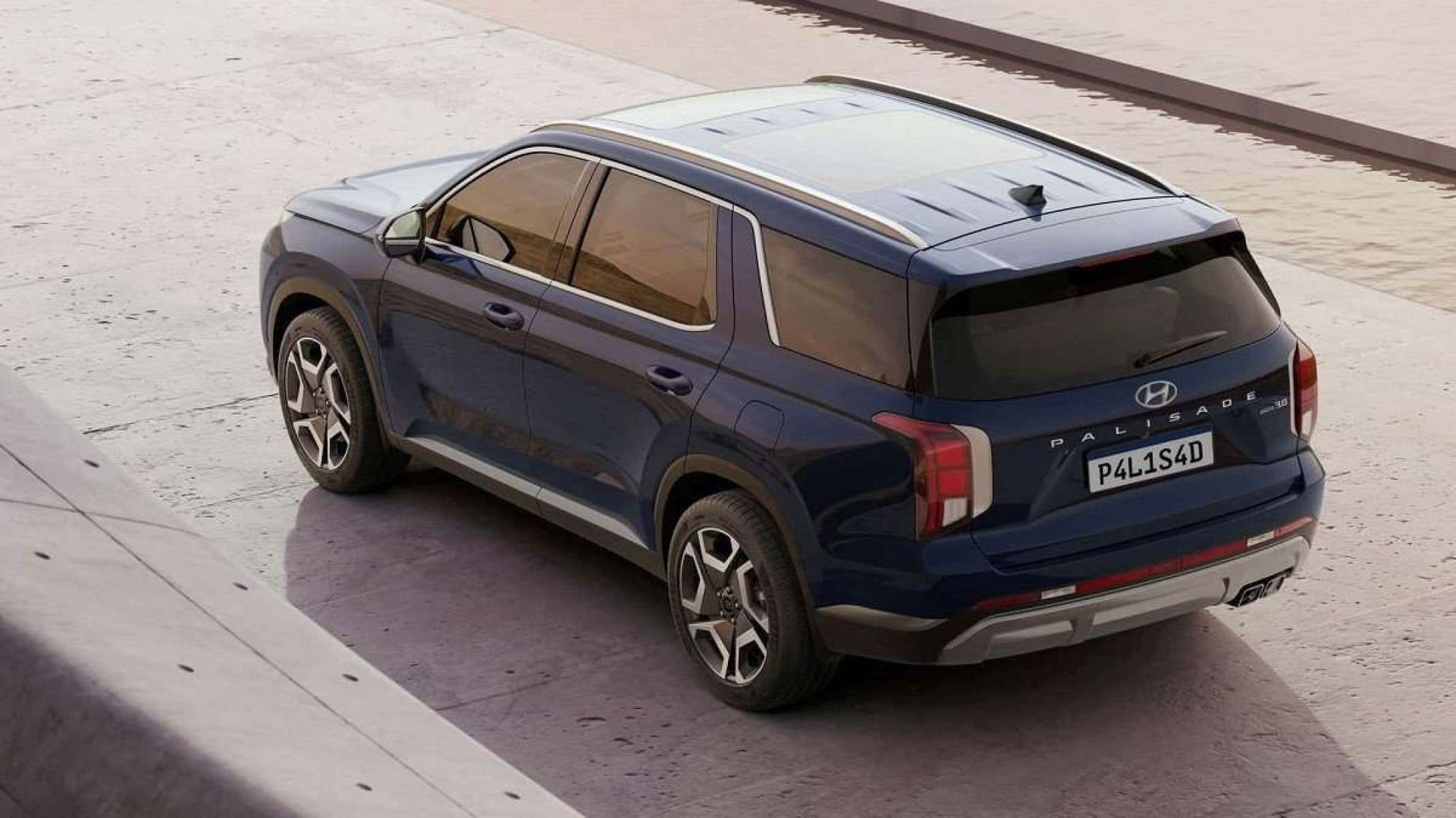 Hyundai Palisade azul marinho visto pela traseira com detalhes da lateral esquerda. Veículo está estacionado em chão branco e recebe luz do sol em sua dianteira