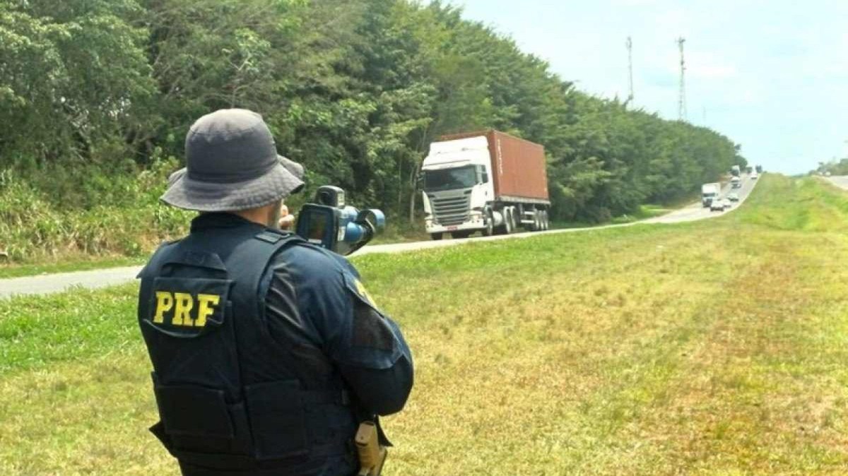 Policial Rodoviário Federal fiscalizando velocidade com um radar móvel em mãos