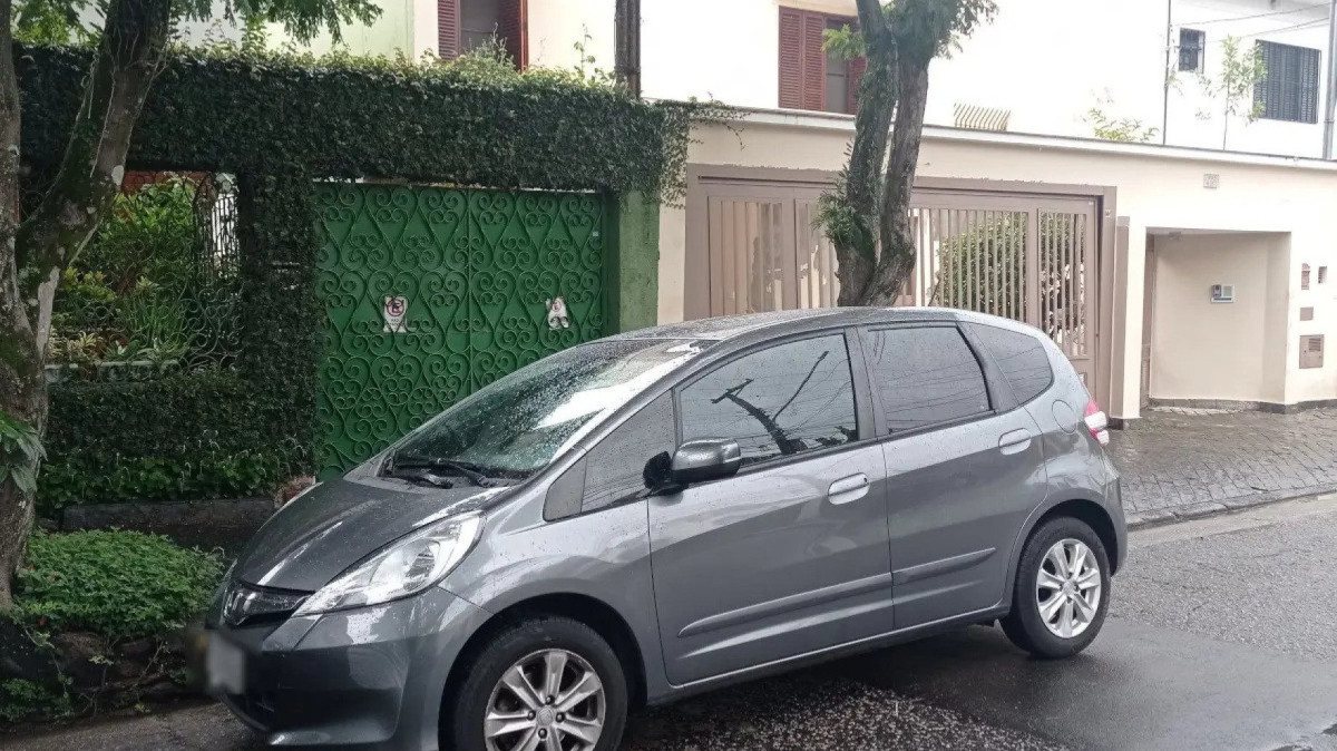 Honda Fit cinza estacionado na frente de um portão de garagem 