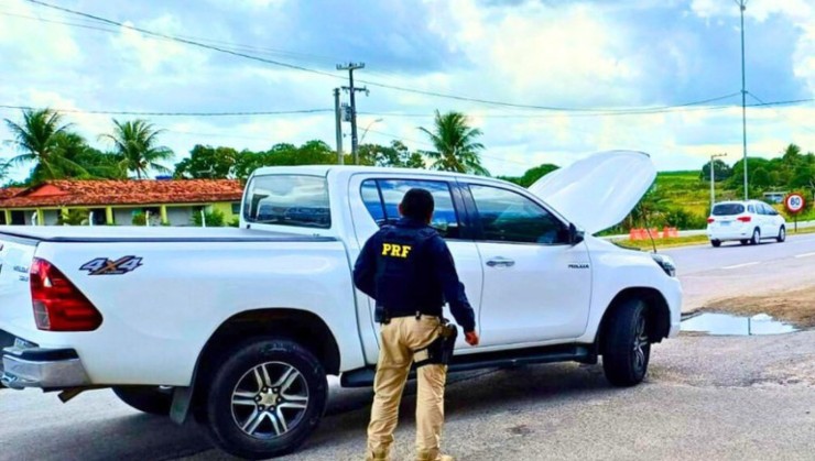 Policial rodoviário federal ao lado de picape branca apreendida